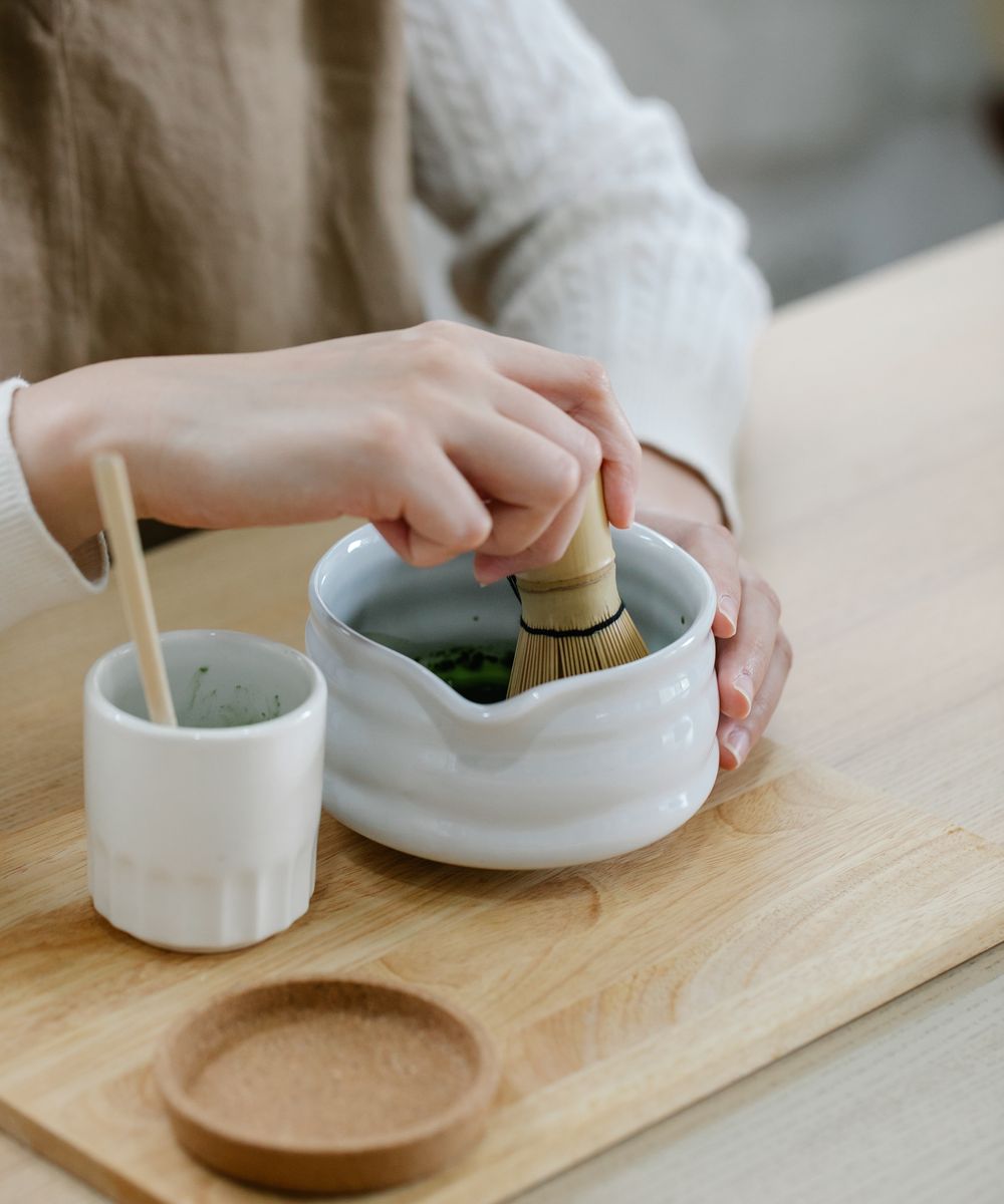 A bowl of bright green matcha being whisked at home