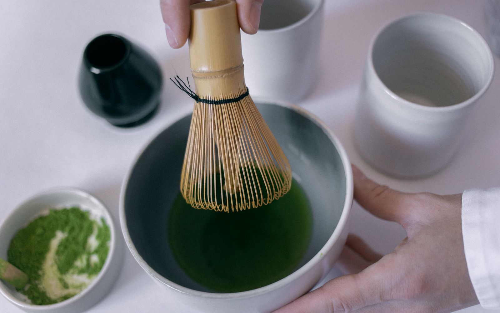 Bright green matcha being whisked in a ceramic bowl